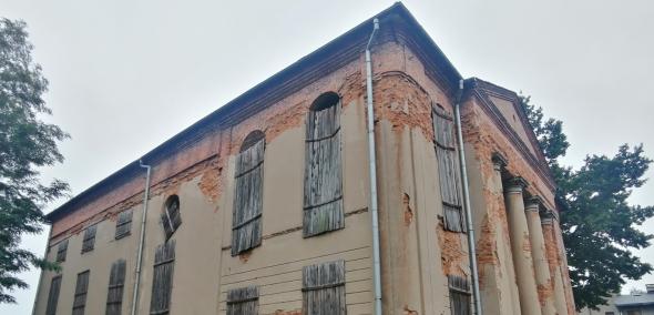 Opuszczony budynek dawnej synagogi w Kępnie. Obsypana fasada budynku, okna zabite drewnianymi deskami.