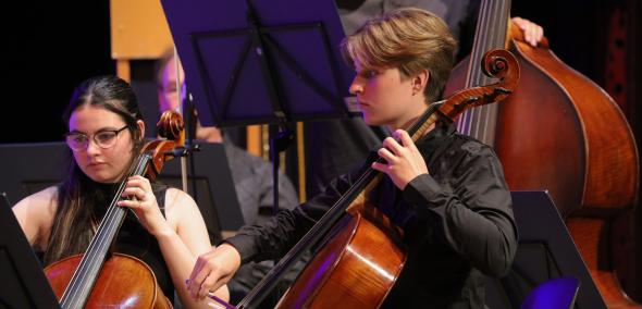 Dziewczyna i chłopak grają na instrumentach smyczkowych podczas występu Orkiestry Niemiecko-Polskiej.