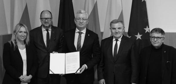 czterech prezydentów polskich miast na tle flag Polski i Unii Europejskiej prezentuje dokument