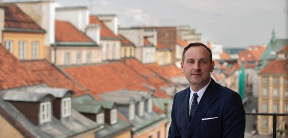 Dr Jarosław Trybuś, w tle widoczne dachy warszawskiego Starego Miasta, fot. Dawid Żuchowicz