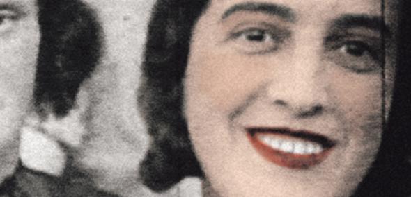 Uśmiechnięta ciemnowłosa kobieta pochodzenia żydowskiego. Jej usta pomalowane są na czerwono.