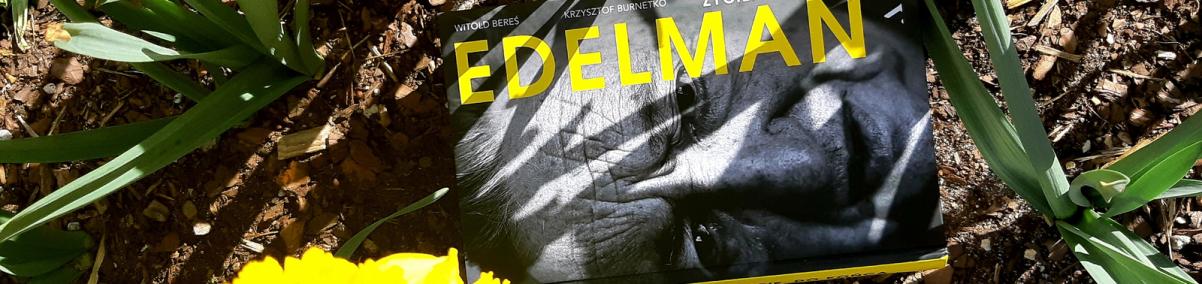 Książka "Marek Edelman - biografia" leży na trawniku, między kwitnącymi żółtymi żonkilami