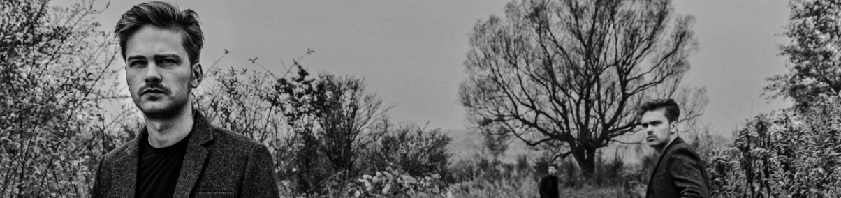 Czarno-białe zdjęcie. Dwóch mężczyzn na polnej drodze.