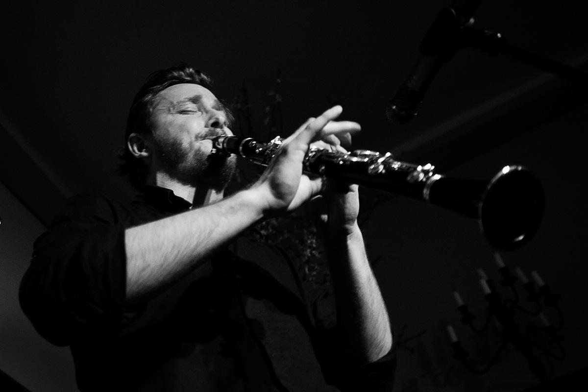 Czarno-białe zdjęcie mężczyzny (Paweł Szamburski). Gra na klarnecie.