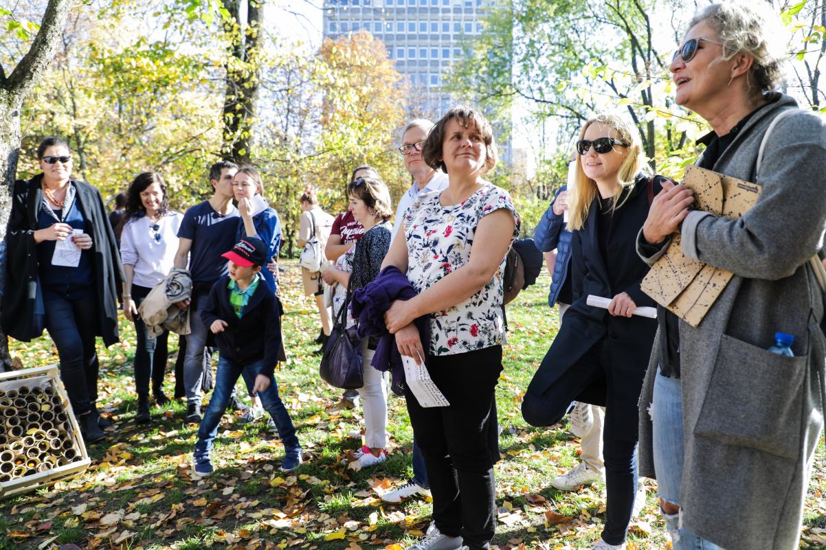 W parku w jesiennych barwach stoi grupa ludzi i opowiadają sobie nawzajem jakieś historie