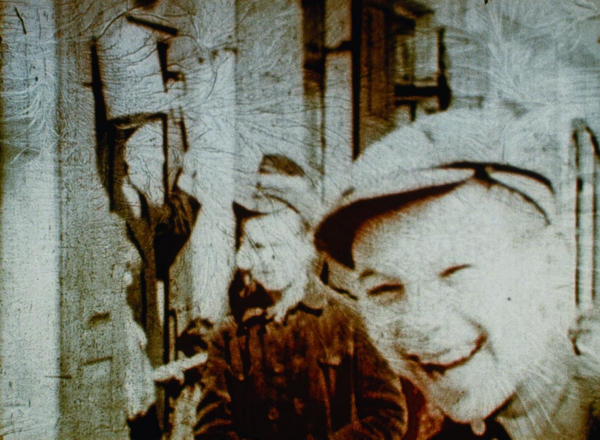 Kadr z filmu "Trzy minuty zawieszone w czasie". Młody chłopak uśmiecha się, za nim stoi mężczyzna.