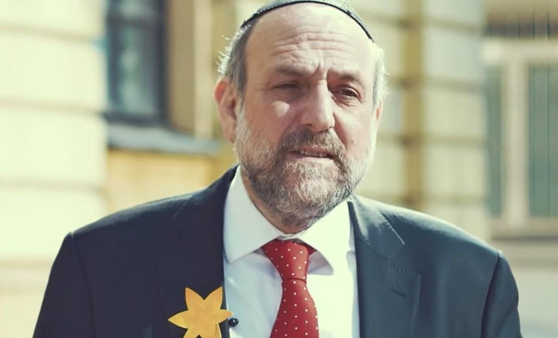 Rabin Michael Schudrich z papierowym żonkilem przypiętym do garnituru.