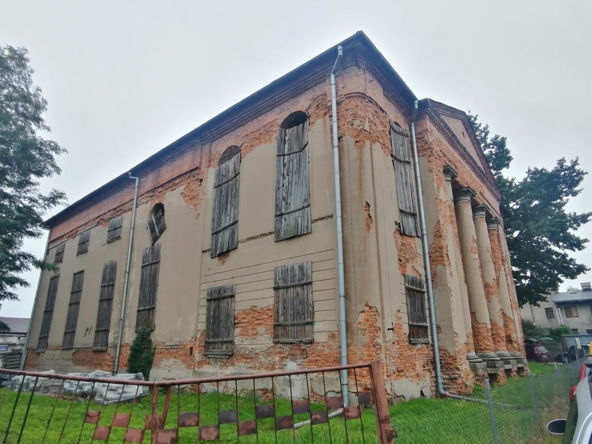 Opuszczony budynek dawnej synagogi w Kępnie. Obsypana fasada budynku, okna zabite drewnianymi deskami.