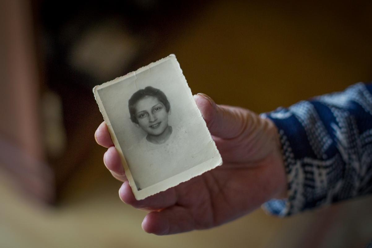 Krystyna Budnicka trzyma w dłoni swoje czarno-białe zdjęcie z dzieciństwa.