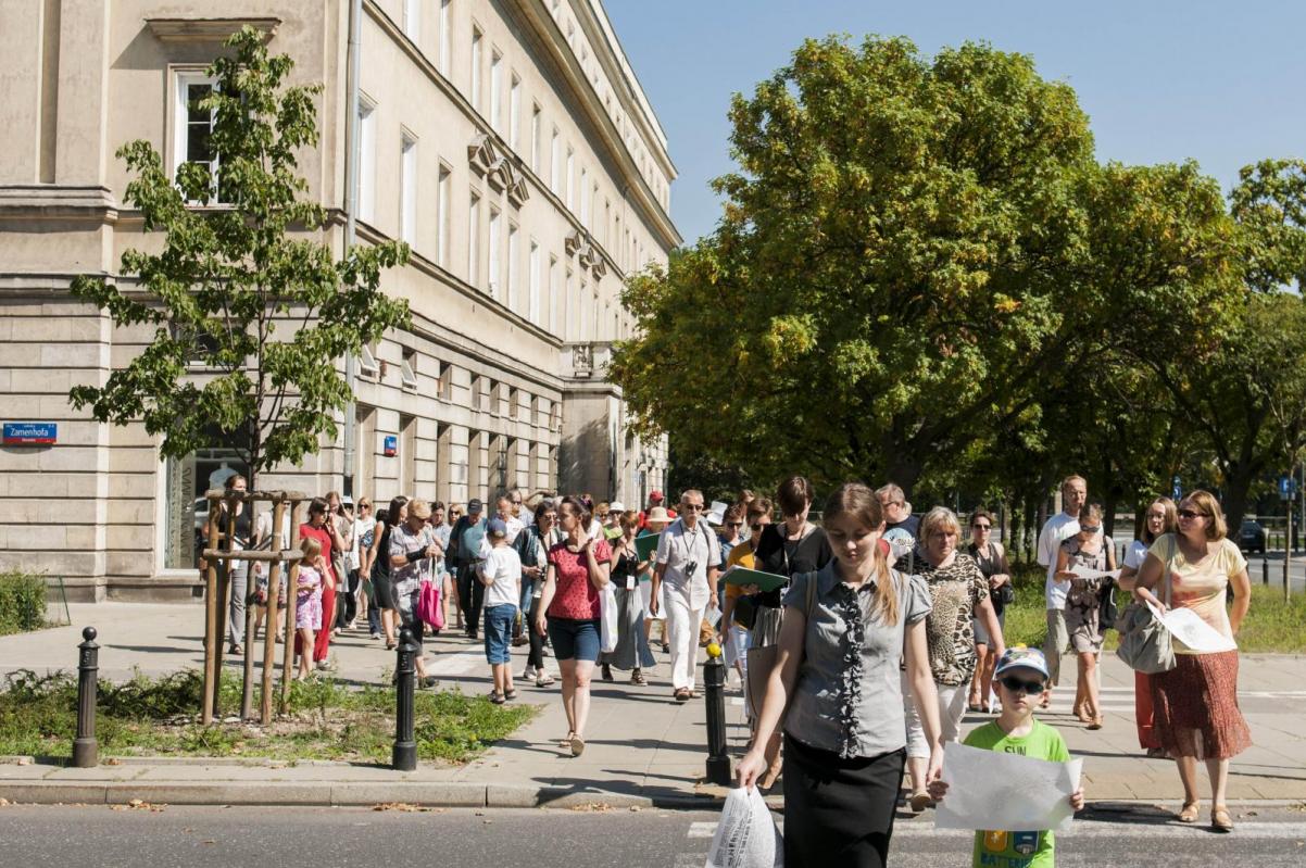 duża grupa uczestników spaceru miejskiego organizowanego przez Muzeum Polin na tle budynku przy ulicy Zamenhofa w Warszawie