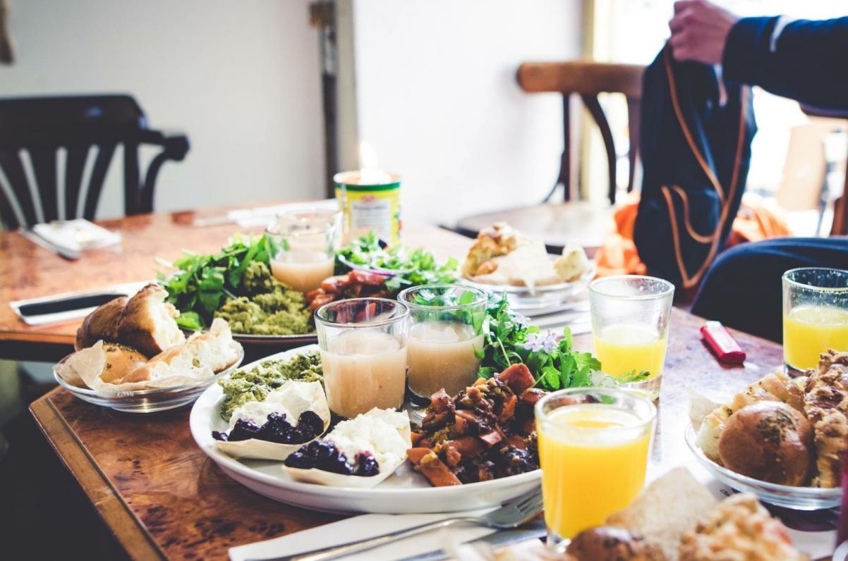 Warsztaty kulinarne - talerze pełne jedzenia i szklanki z sokiem pomarańczowym stoją na stole.