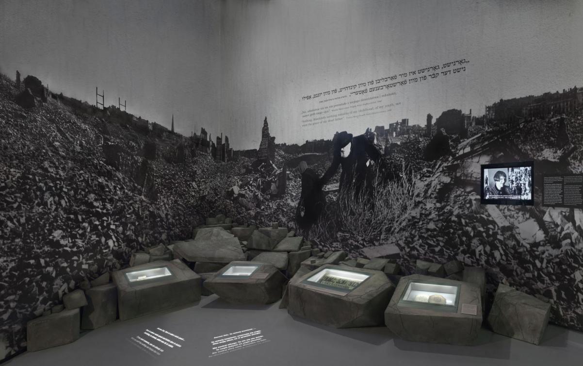 Na zdjęciu: Fragment galerii "Zagłada" z przedstawieniem powiększonego zdjęcia powojennych ruin Warszawy. Po gruzowisku z trudem przemieszczają się dwie osoby.