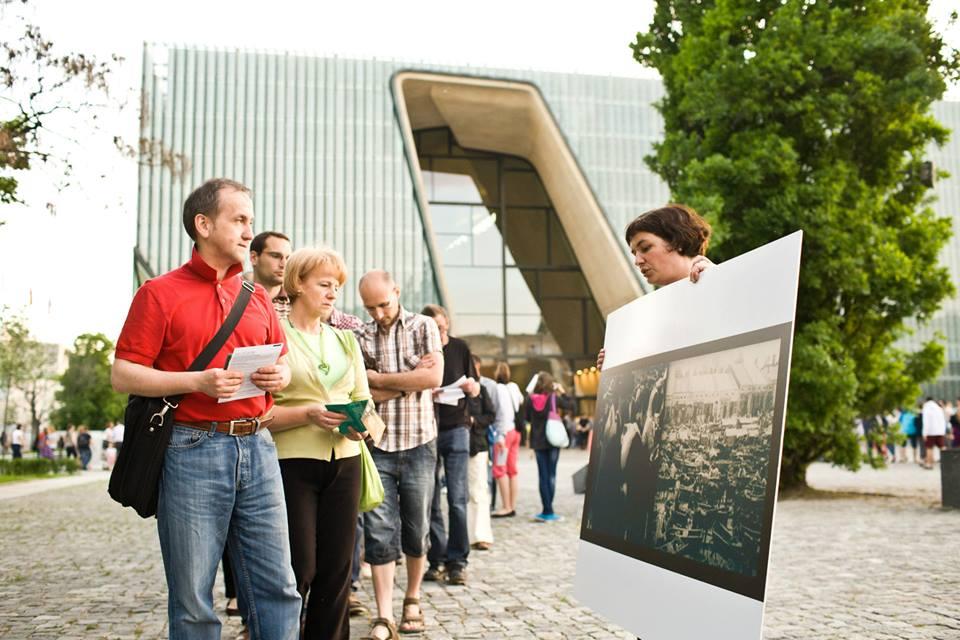 Grupa osób na spacerze na skwerze przy Muzeum POLIN.