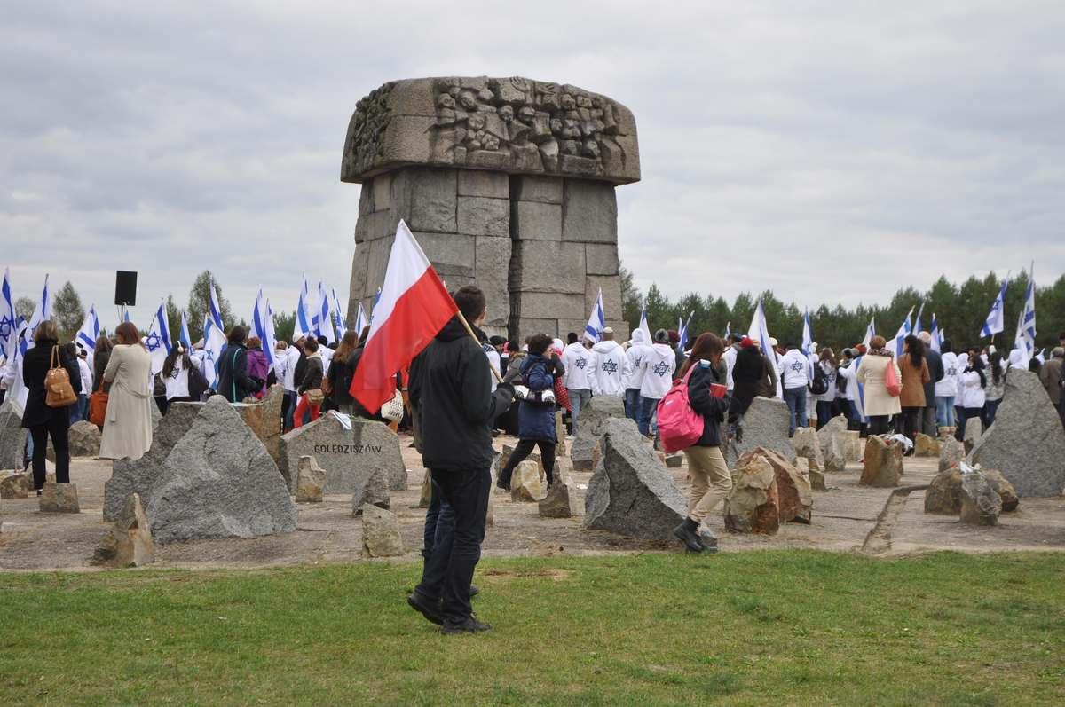 Mężczyzna z biało-czerwoną flagą przy pomniku w Treblince.