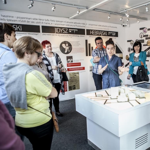 Grupa zgromadzona wokół makiety podczas spotkania po wystawie "Muzeum na kółkach" z przewodniczką.