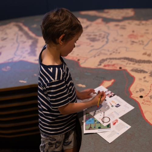 The boy fills out the worksheets at the Core Exhibition. The worksheets are located at the display showing the map.