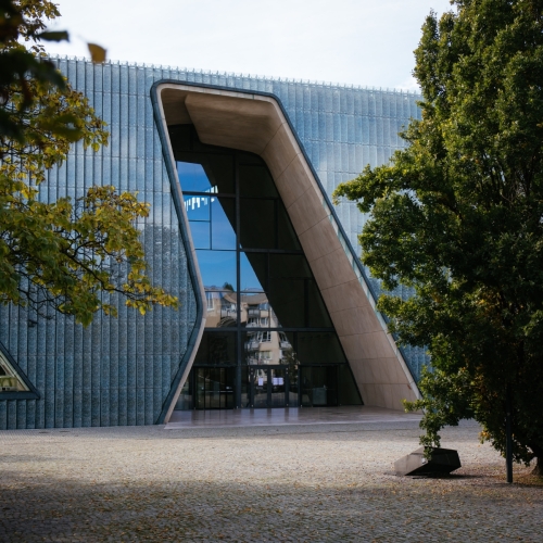 Budynek Muzeum POLIN wśród drzew.