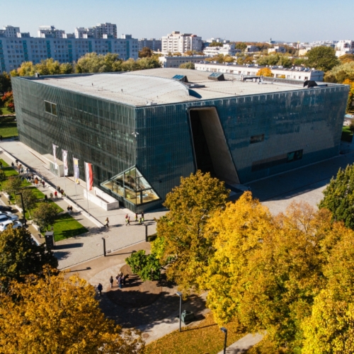 Budynek Muzeum POLIN wśród jesiennych drzew.