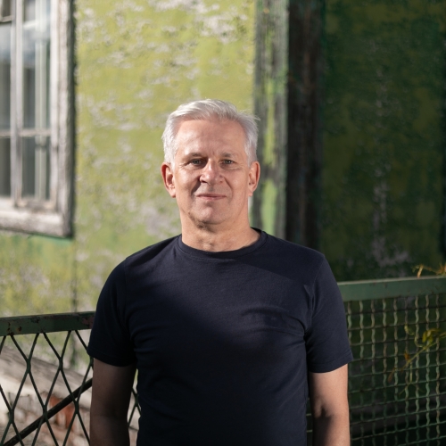 Marek Kołcon przed drewnianym budynkiem w Zamościu