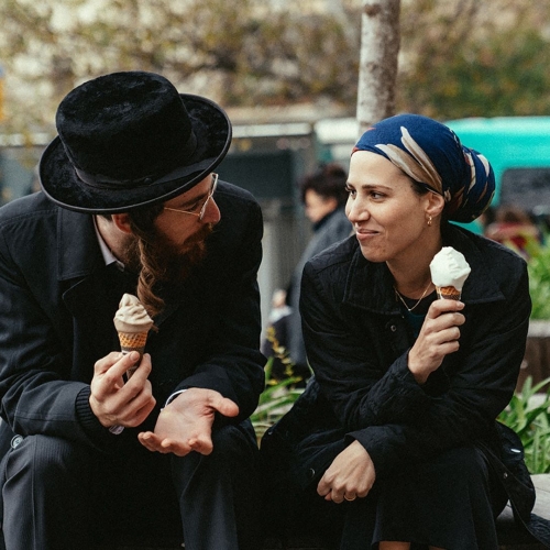 Para żydowska siedzi na krawędzi fontanny i je lody