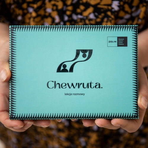 Ktoś trzyma przed sobą pudełko z kartami do gry "Chewruta. Lekcje rozmowy".