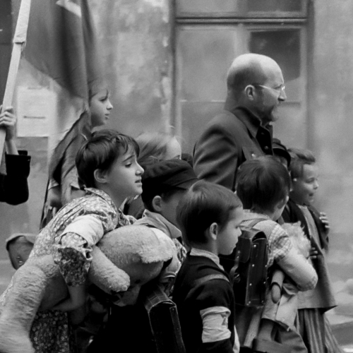 Czarno-biały kadr z filmu "Korczak". Grupa dzieci stoi obok Janusza Korczaka.